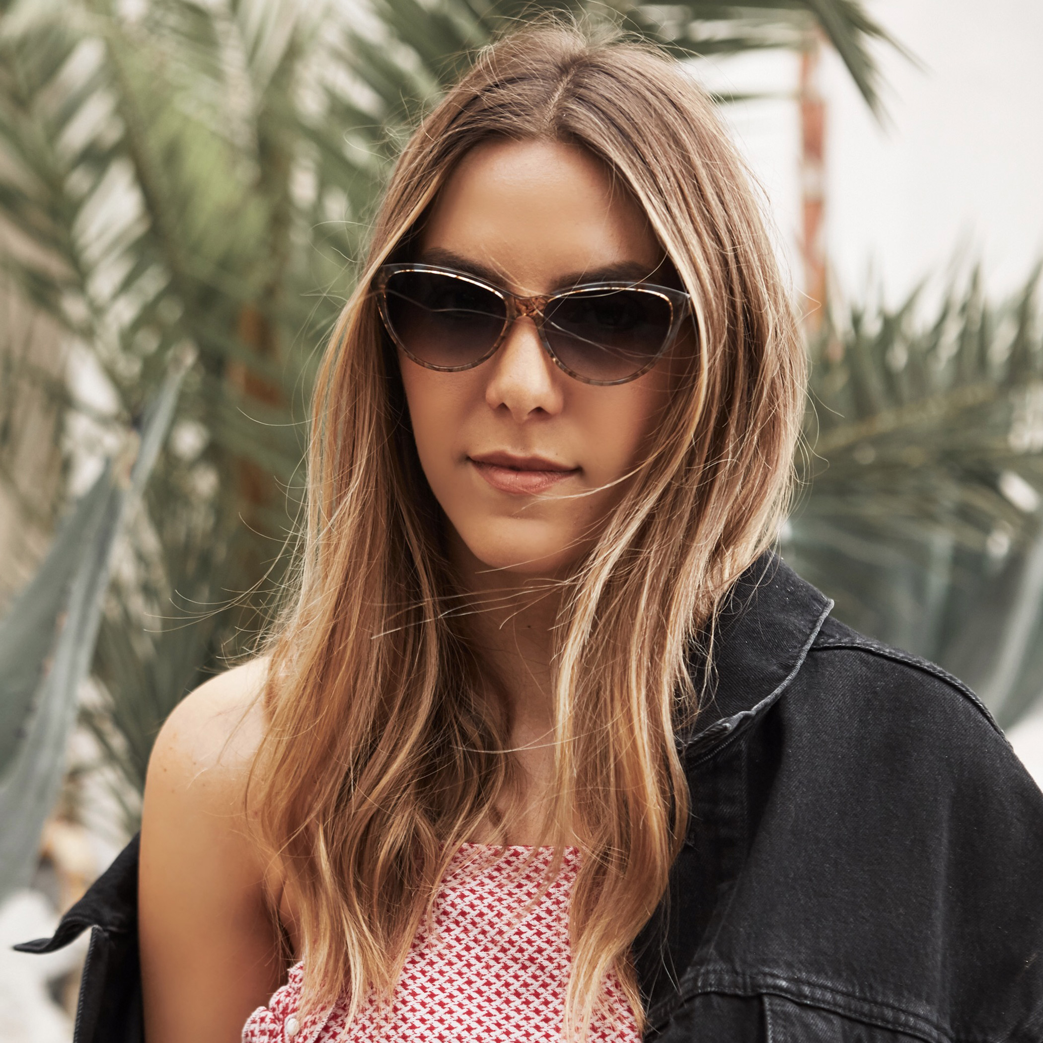 Woman wearing cat-eye sunglasses with tortoiseshell frame.
