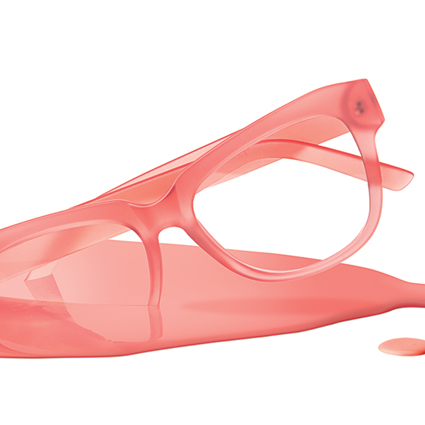 Translucent pink eyeglasses lying on a matching pink surface.