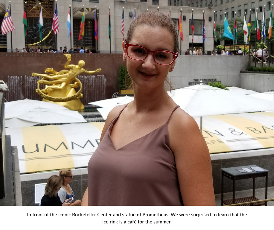 Woman wearing a mauve top in front of the Rockefeller Center and statue of Prometheus. Text reads: "In front of the iconic Rockefeller Center and statue of Prometheus. We were surprised to learn that the ice rink is a café for the summer."