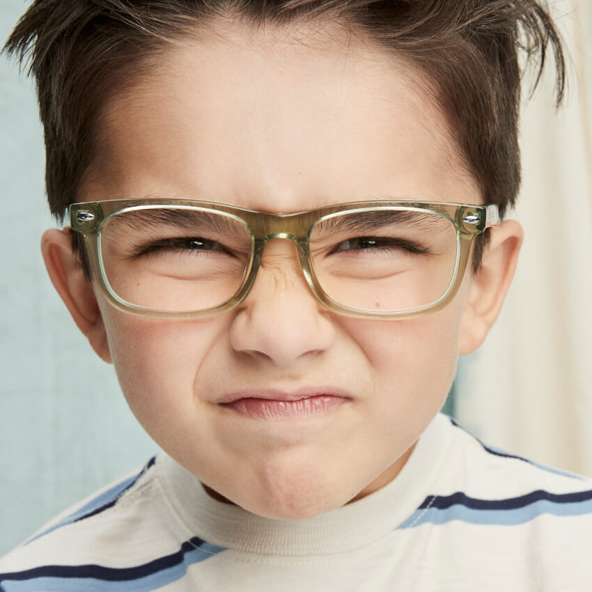 Child wearing light green semi-transparent rectangular eyeglasses with metal rivets on temples.