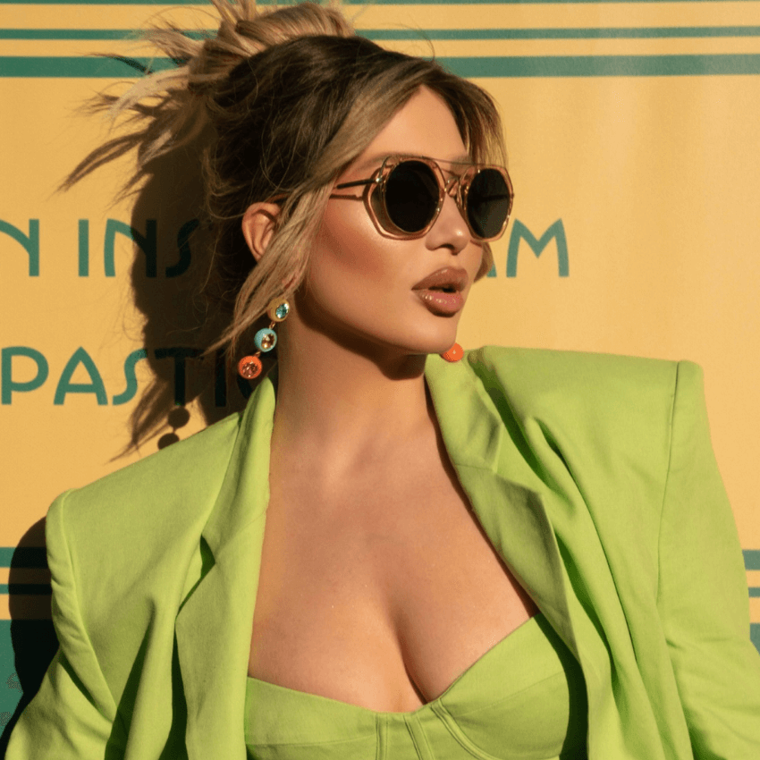 Woman wearing oversized sunglasses, lime green blazer, and multi-colored earrings. Background text partially visible: "IN INS... PASTI...".