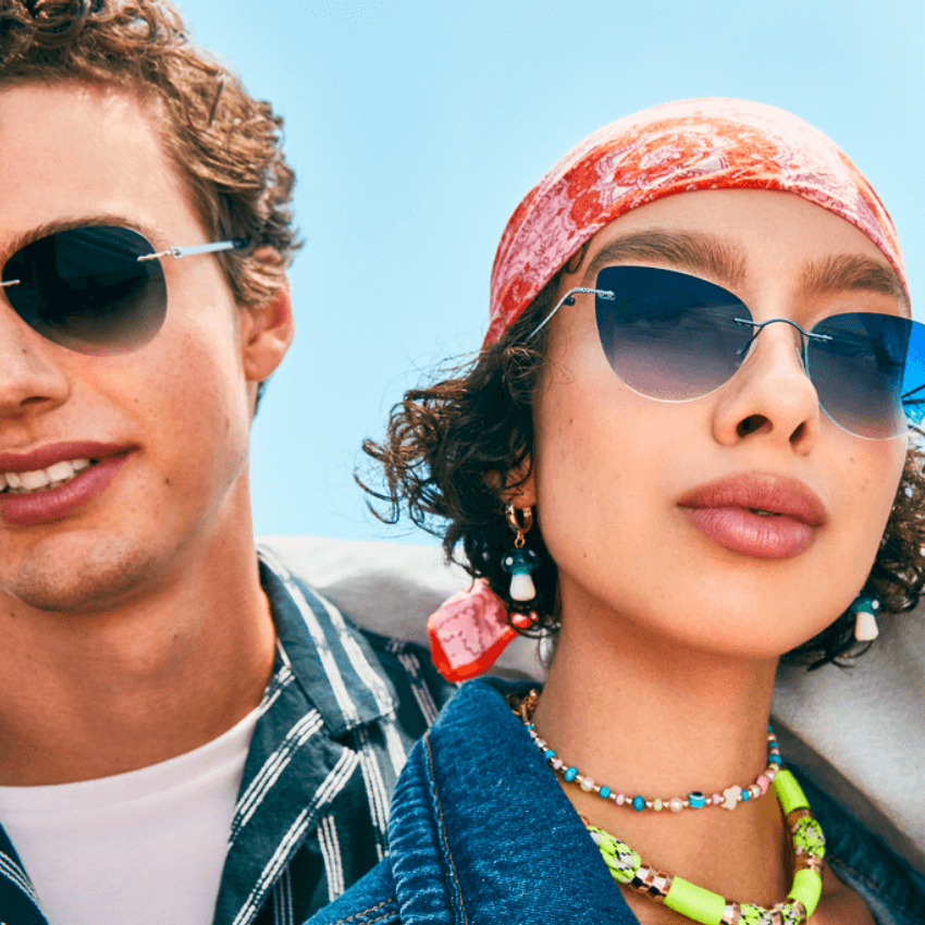 Two people wearing stylish sunglasses. The person on the right also wears a colorful headscarf and jewelry.