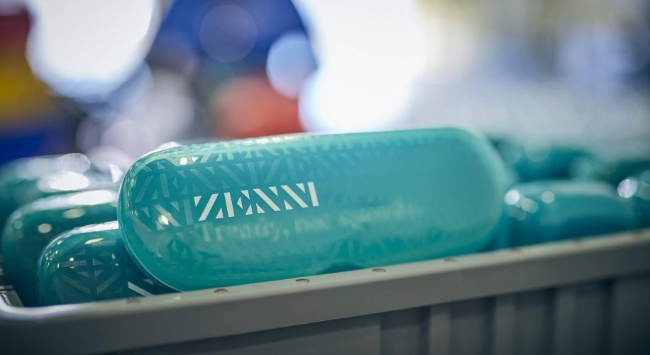 Zenni turquoise eyewear cases with geometric patterns stacked in a container.