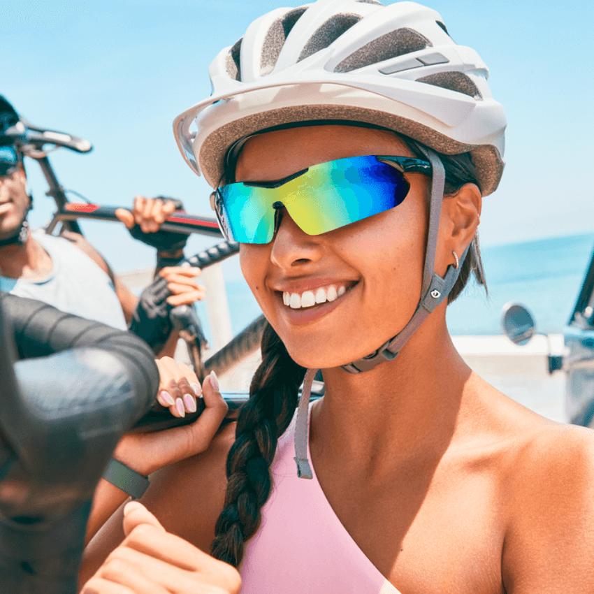 Woman wearing a white bicycle helmet and reflective blue-green sports sunglasses, smiling.
