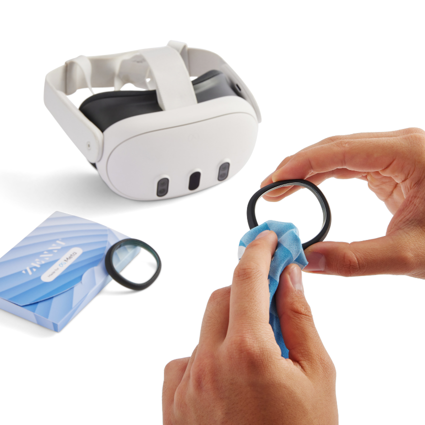 Hands cleaning a round lens with a blue cloth, VR headset and packaging labeled "ZARA" in the background.
