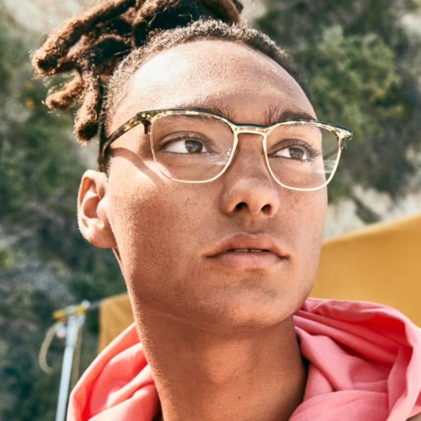 Person wearing clear-framed glasses and a pink hoodie.