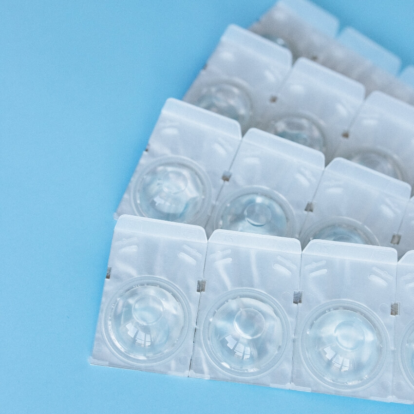 Blister packs of clear contact lenses on a light blue background.