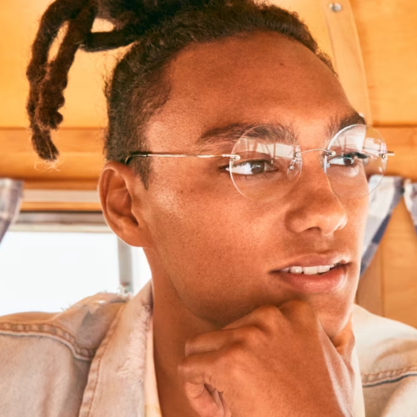 Man wearing frameless, round-lens glasses with a thoughtful expression.
