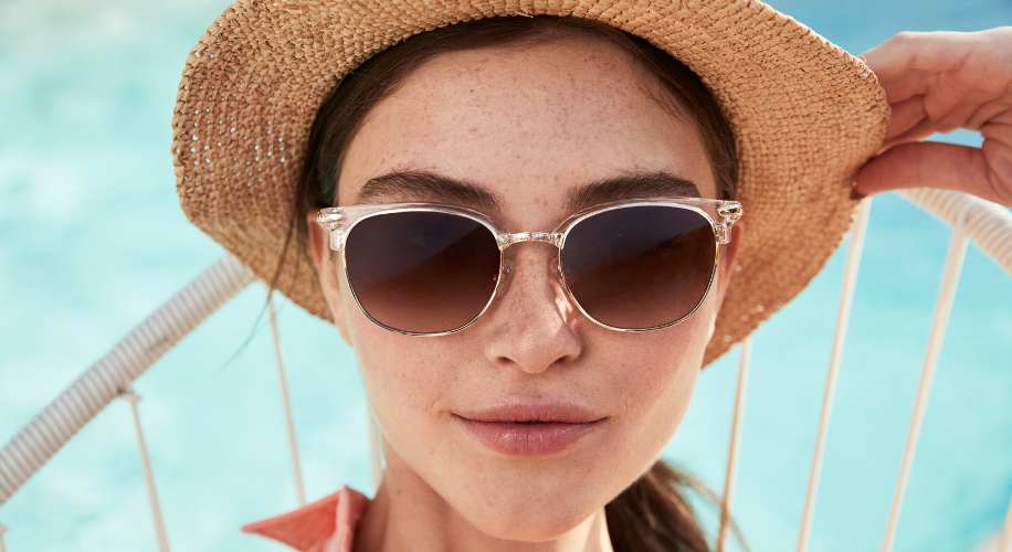 Woman wearing clear-frame sunglasses and a straw hat.