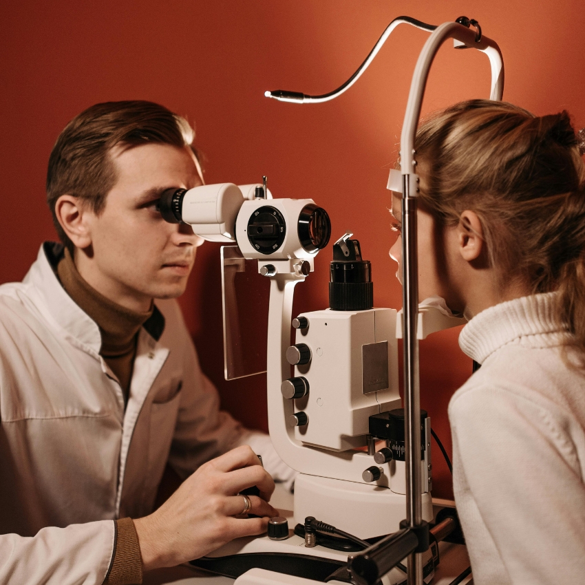Optometrist using a slit lamp to examine a patient's eyes.