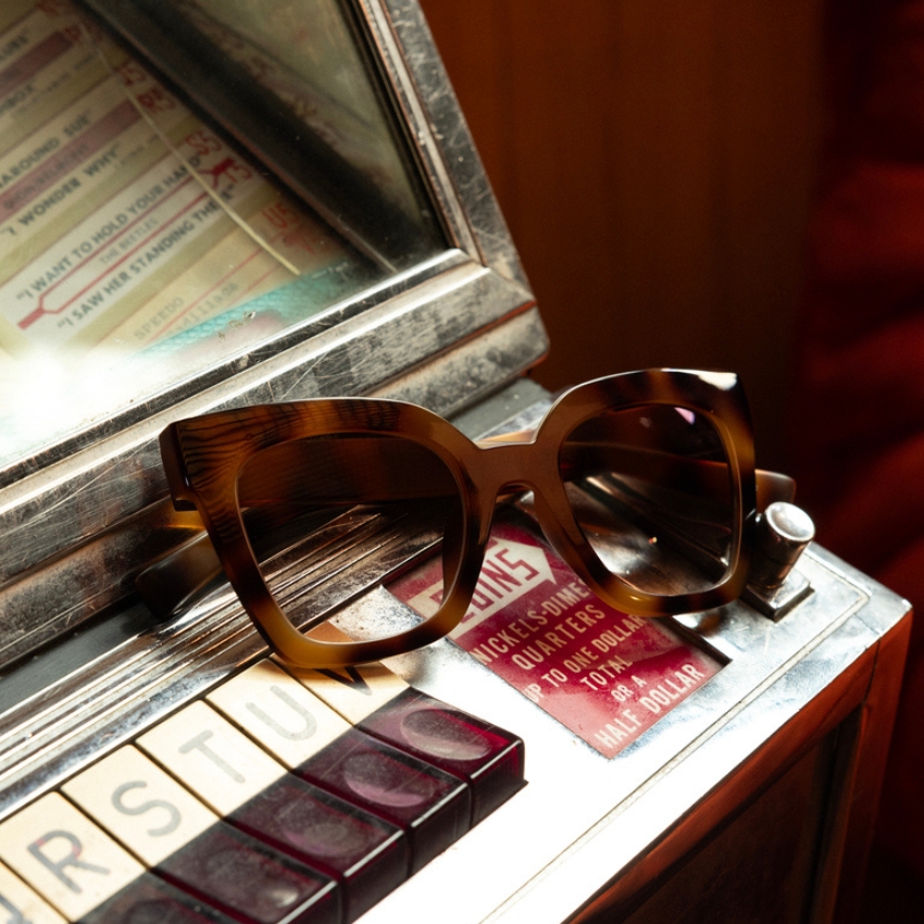 Tortoiseshell sunglasses with thick frames resting on vintage jukebox buttons.