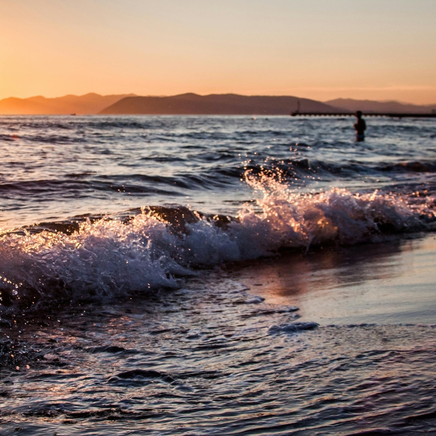 Waves gently crashing on the shore at sunset.