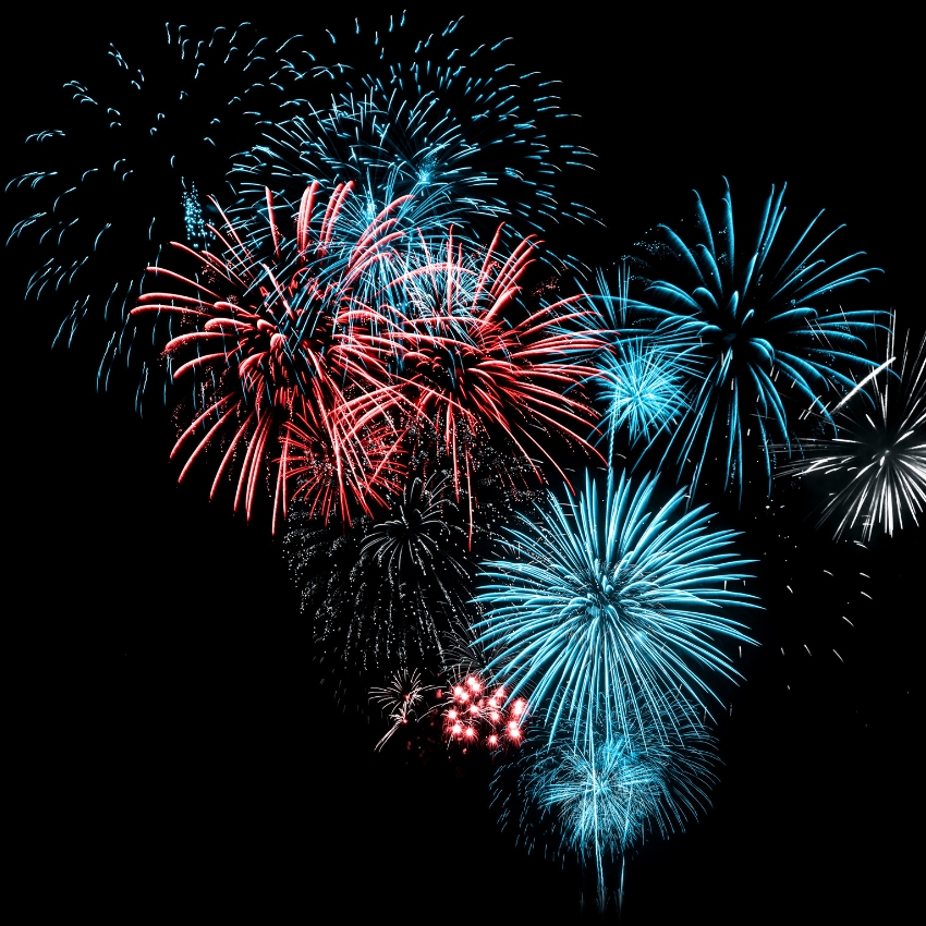 Red, blue, and white fireworks bursting in various patterns against a black sky.